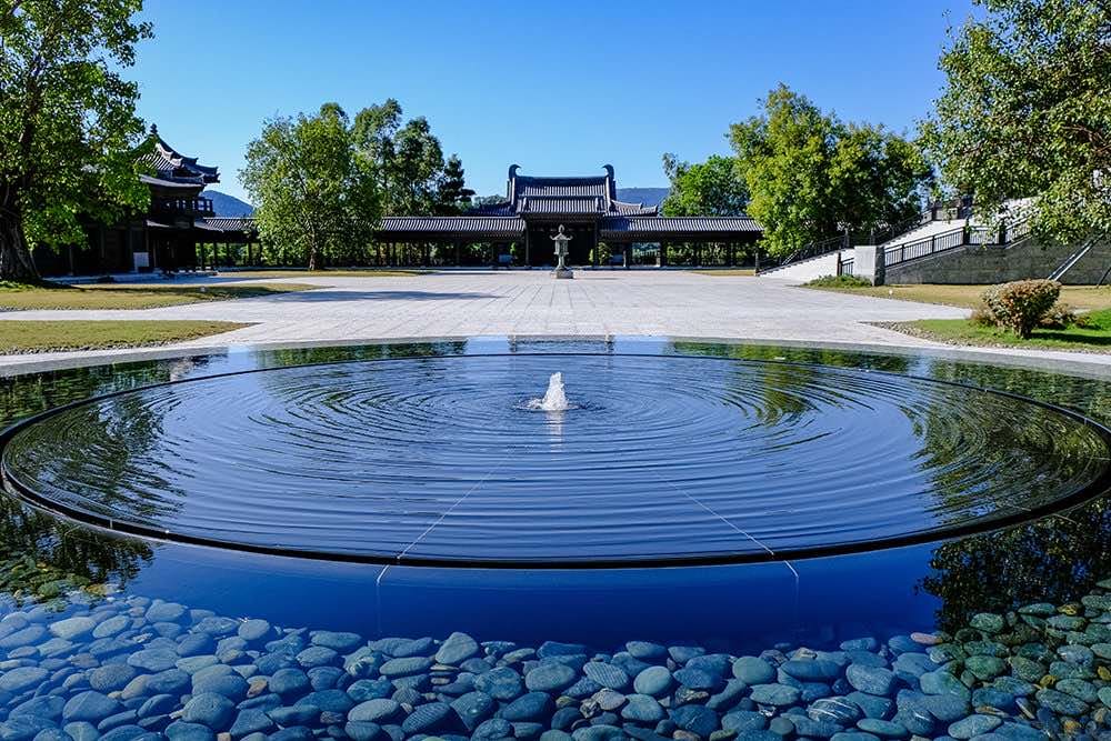 A circular pool of still water with the halls beyond.